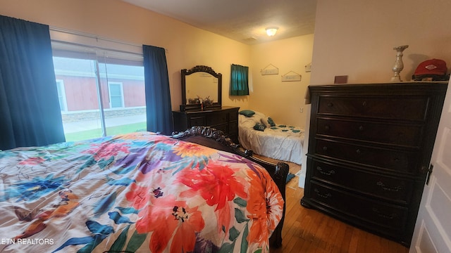 bedroom with access to exterior and hardwood / wood-style flooring