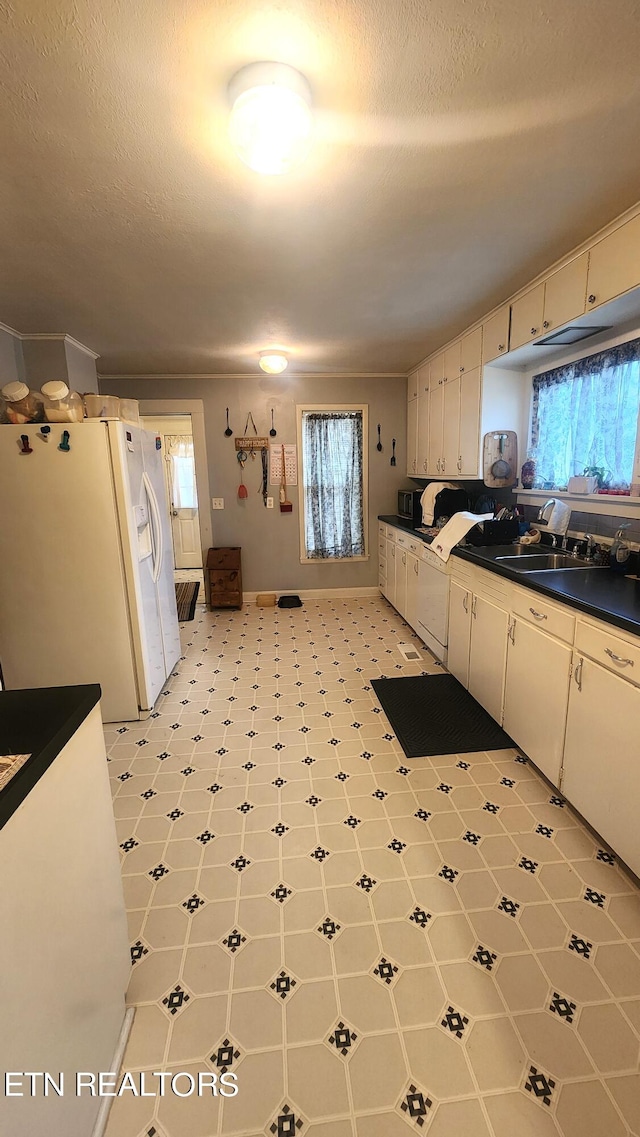 kitchen featuring sink, a textured ceiling, white refrigerator with ice dispenser, and white cabinets