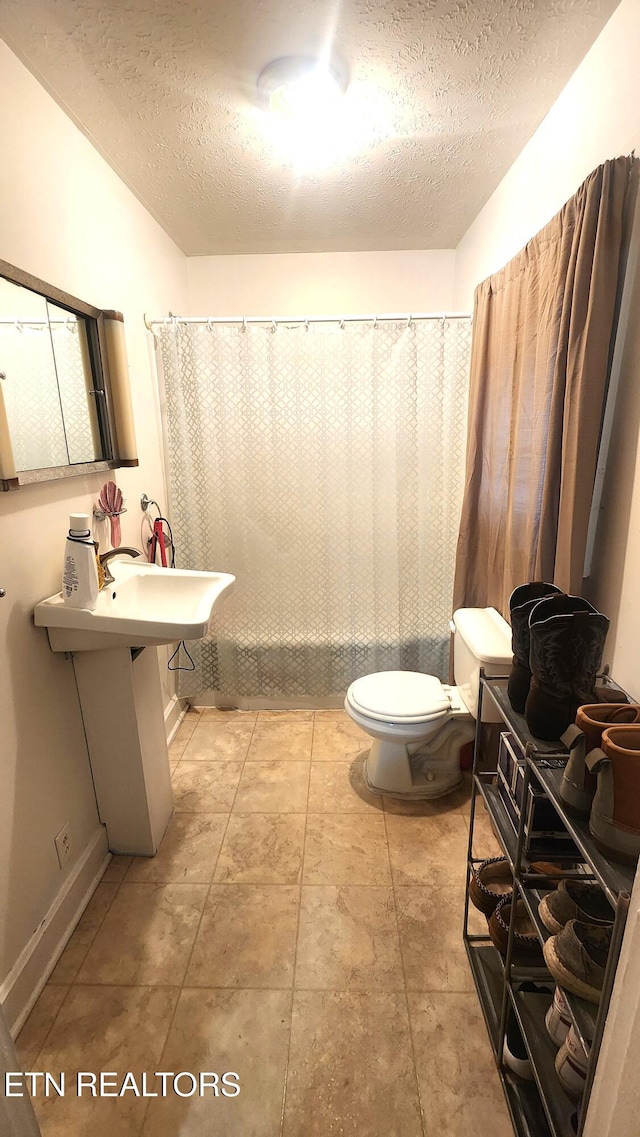 bathroom with a shower with curtain, a textured ceiling, and toilet