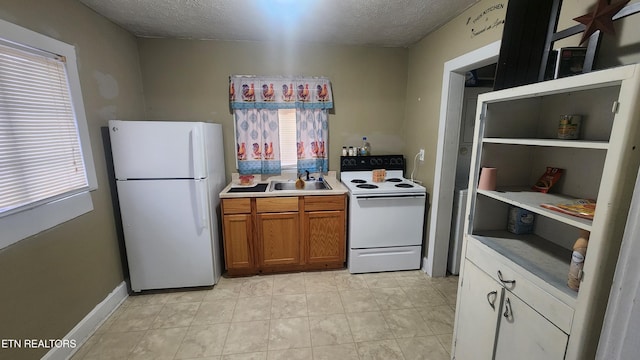 kitchen featuring a textured ceiling, a wealth of natural light, sink, and white appliances