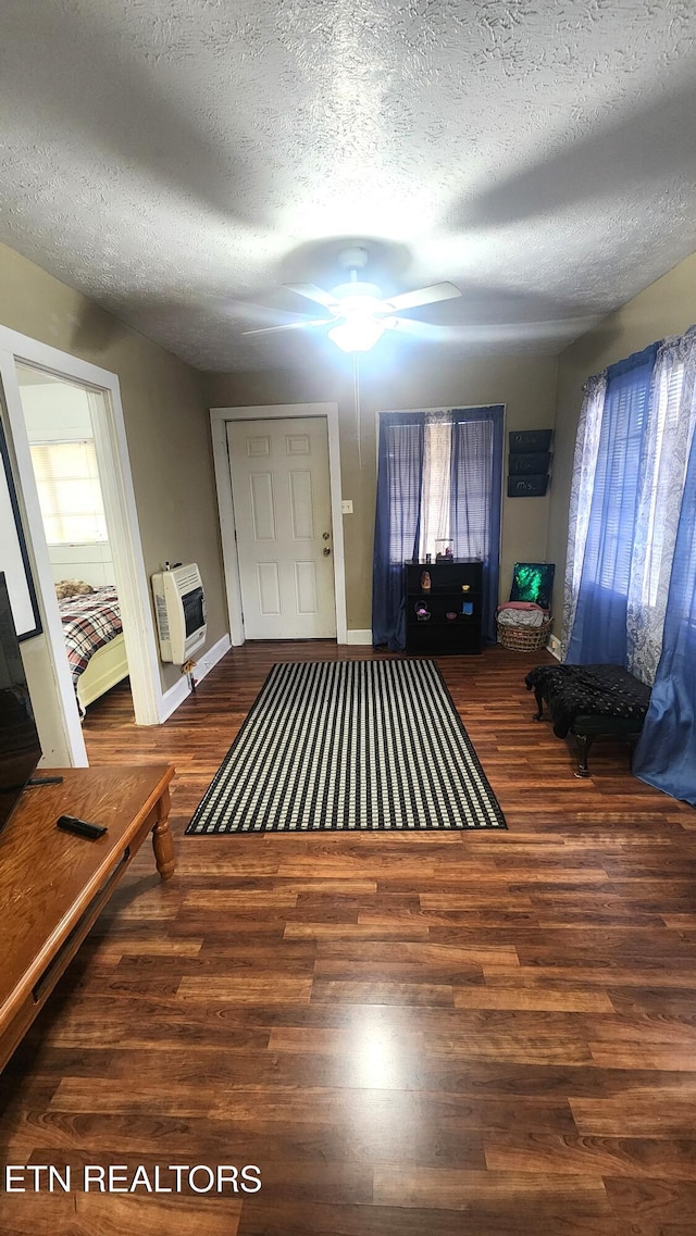 foyer entrance featuring dark wood-type flooring, a textured ceiling, heating unit, and ceiling fan