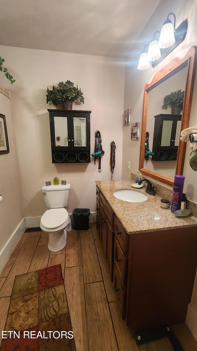 bathroom featuring vanity, toilet, and hardwood / wood-style floors