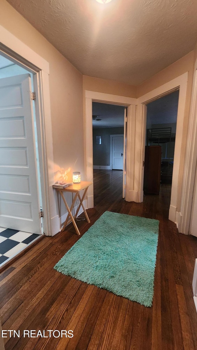 corridor with dark wood-type flooring and a textured ceiling