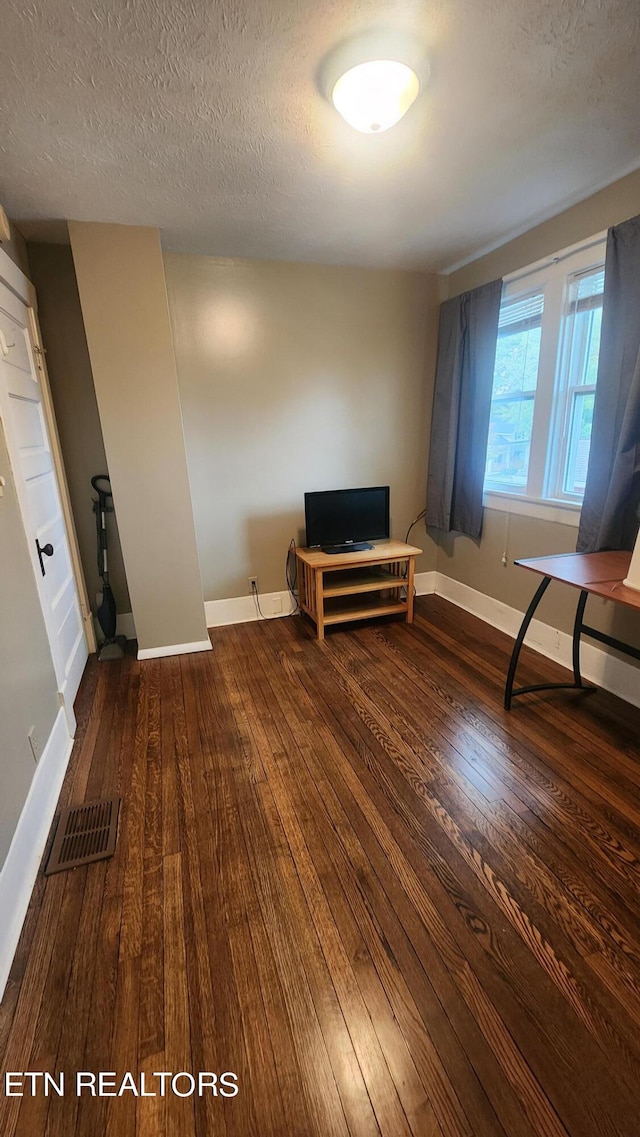 unfurnished room with a textured ceiling and dark hardwood / wood-style flooring