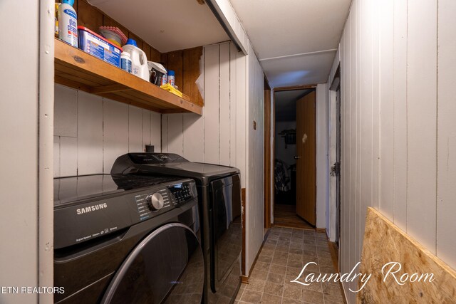 clothes washing area with wooden walls and washing machine and clothes dryer