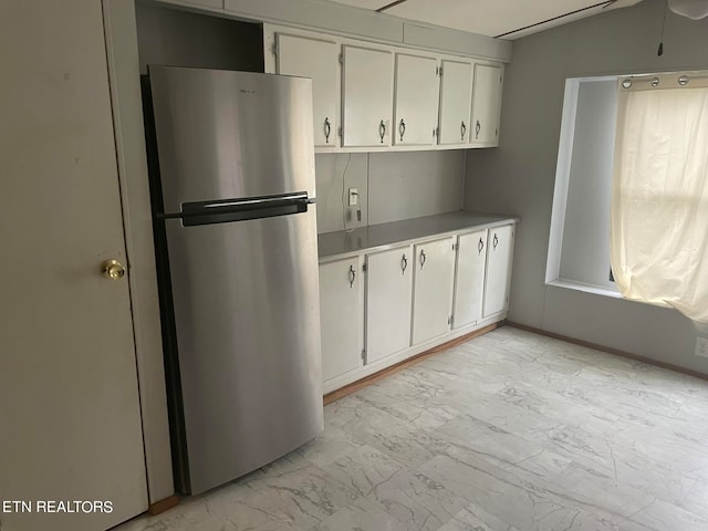 kitchen with stainless steel fridge and white cabinetry