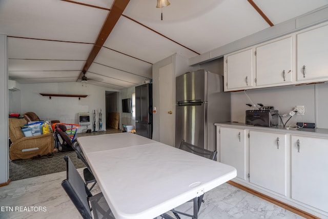 kitchen featuring an AC wall unit, stainless steel refrigerator, vaulted ceiling, and white cabinets