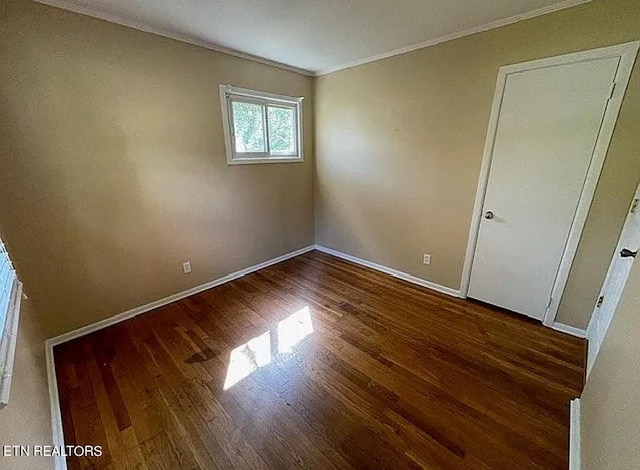 unfurnished room featuring crown molding and dark wood-type flooring