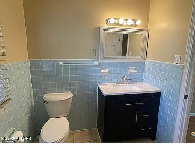 bathroom with vanity, toilet, tile walls, and tile patterned flooring