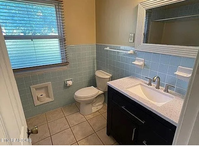 bathroom with vanity, toilet, tile walls, and tile patterned flooring