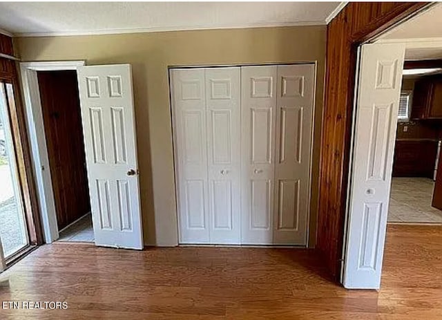 unfurnished bedroom featuring crown molding, hardwood / wood-style flooring, and a closet