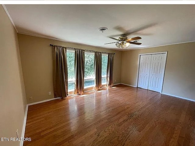 unfurnished bedroom featuring a closet, ceiling fan, hardwood / wood-style flooring, and ornamental molding