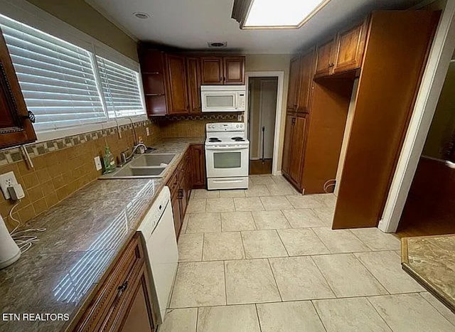 kitchen with light tile patterned flooring, tasteful backsplash, sink, and white appliances