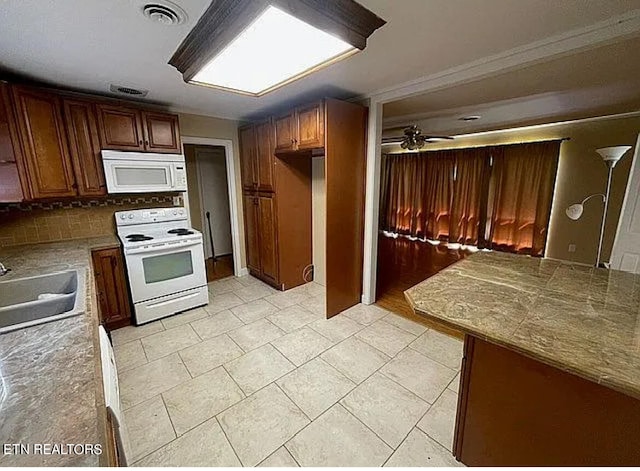 kitchen featuring tasteful backsplash, ceiling fan, light tile patterned flooring, sink, and white appliances