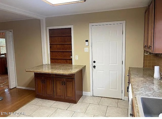 kitchen with tasteful backsplash, light tile patterned flooring, and sink