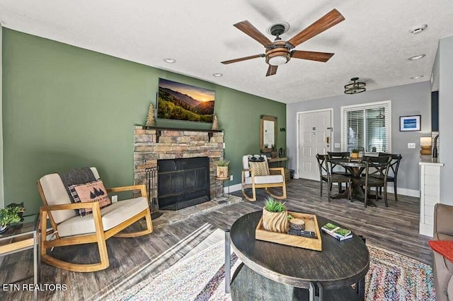 living room with ceiling fan, a textured ceiling, a fireplace, and hardwood / wood-style floors