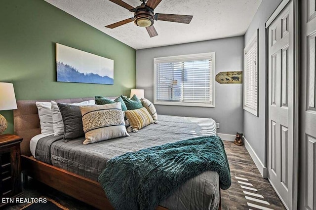 bedroom with a textured ceiling, dark hardwood / wood-style floors, and ceiling fan