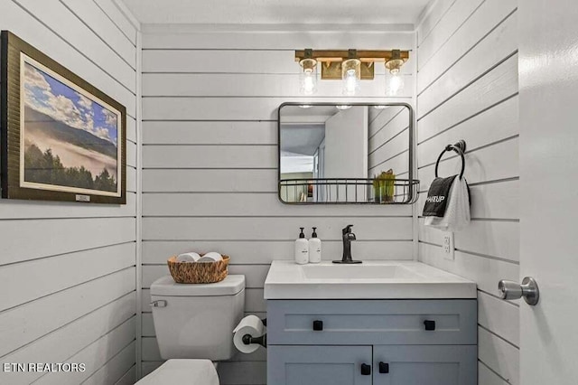 bathroom with vanity, toilet, and wood walls