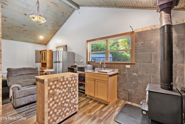 kitchen featuring tile walls, light wood-type flooring, stainless steel refrigerator, sink, and decorative light fixtures