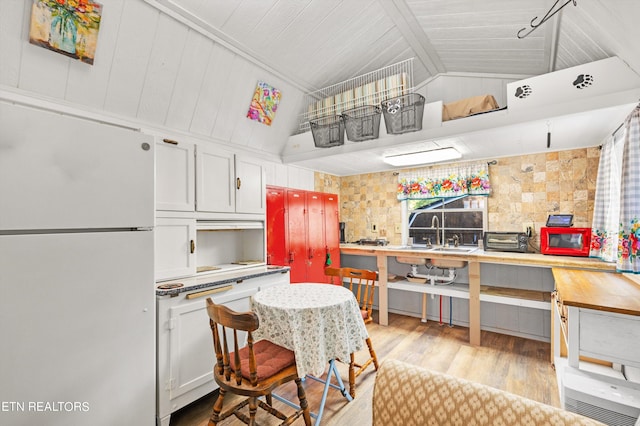 kitchen with lofted ceiling, wood ceiling, light hardwood / wood-style flooring, white cabinetry, and white fridge