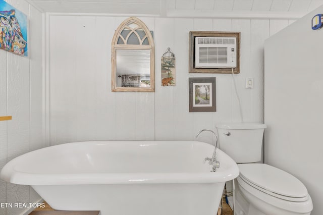 bathroom featuring wooden walls, a wall unit AC, toilet, and a washtub