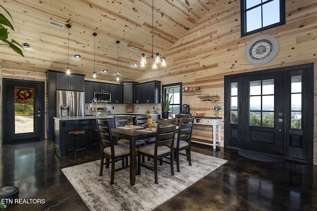 dining room with wood ceiling, an inviting chandelier, wood walls, sink, and high vaulted ceiling