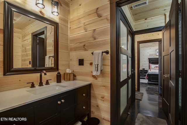 bathroom with concrete flooring, vanity, and wooden walls