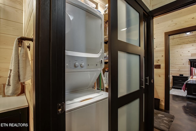 washroom with wood walls and stacked washer / drying machine