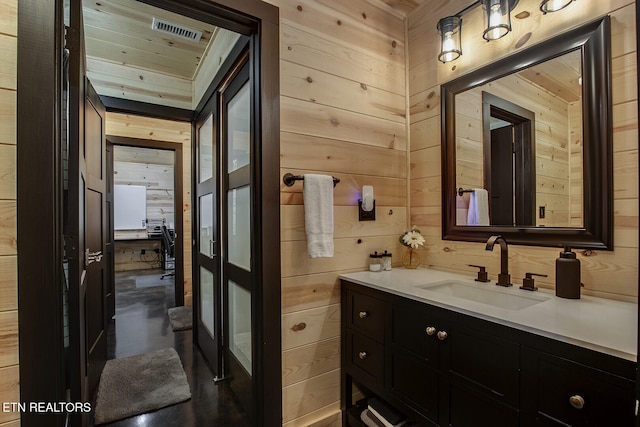 bathroom with wood walls, vanity, and concrete floors