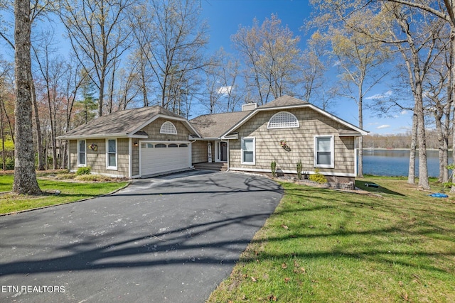 view of front of property with a garage, a front lawn, and a water view