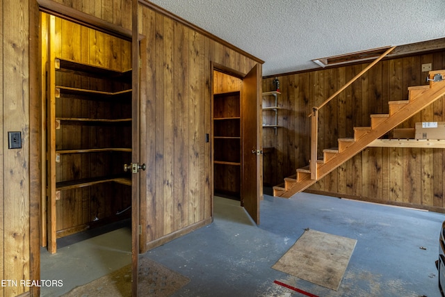 interior space with crown molding, wood walls, and a textured ceiling