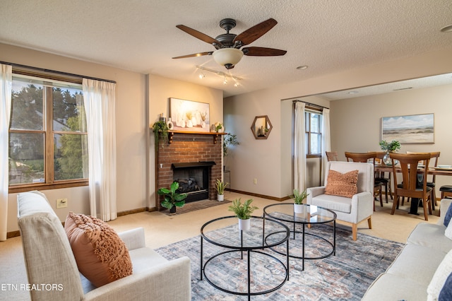 carpeted living room with a brick fireplace, a textured ceiling, a healthy amount of sunlight, and ceiling fan