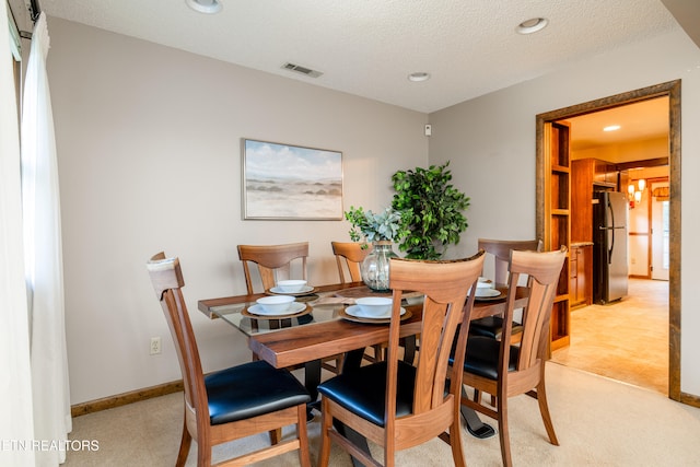 carpeted dining room featuring a textured ceiling