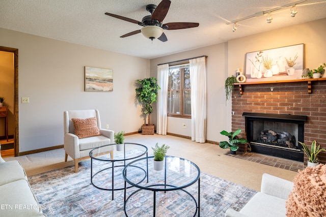 living room featuring a fireplace, a textured ceiling, light carpet, ceiling fan, and track lighting