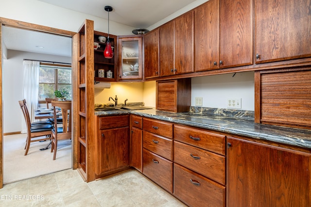 kitchen with sink, dark stone counters, and pendant lighting