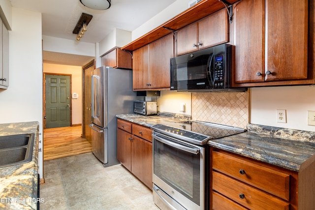 kitchen featuring tasteful backsplash, sink, light wood-type flooring, stainless steel appliances, and dark stone counters