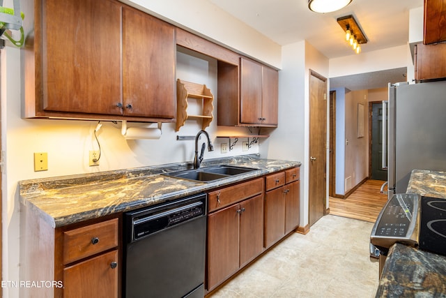 kitchen featuring dark stone counters, stainless steel refrigerator, light hardwood / wood-style flooring, dishwasher, and sink