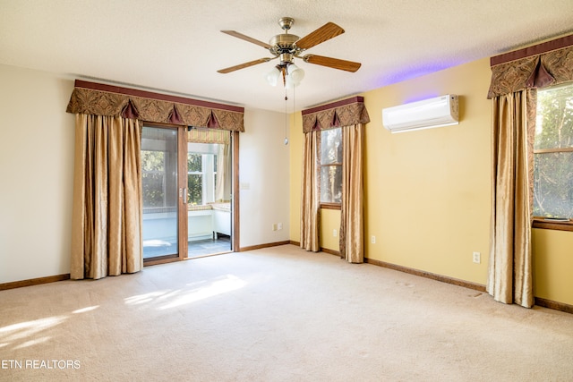 carpeted spare room with a textured ceiling, ceiling fan, an AC wall unit, and a wealth of natural light