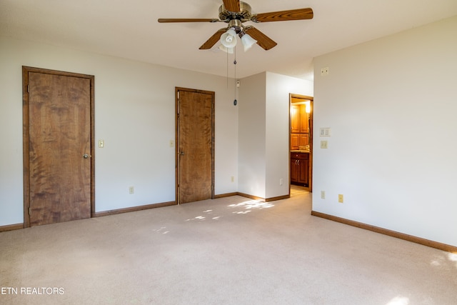 unfurnished bedroom with light carpet, ensuite bathroom, and ceiling fan