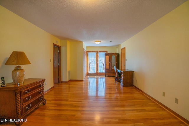 unfurnished room with baseboards, light wood-style floors, and a textured ceiling