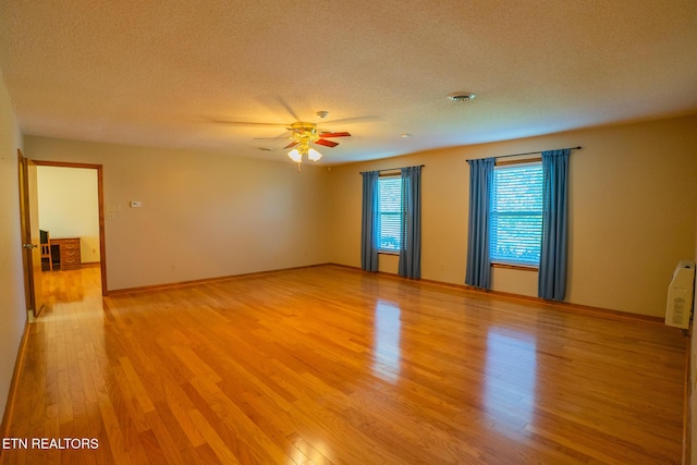 unfurnished room with visible vents, a textured ceiling, light wood-style floors, and ceiling fan