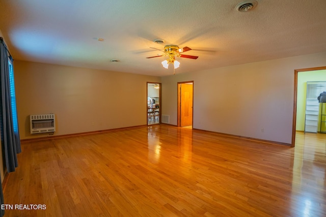 spare room with heating unit, visible vents, light wood-style flooring, and a ceiling fan