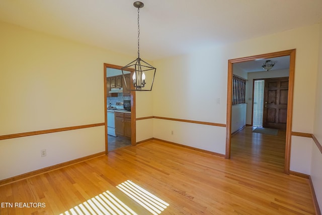 empty room featuring baseboards, light wood-style floors, and a chandelier