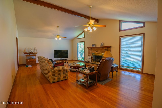 living area featuring visible vents, a fireplace, ceiling fan, wood finished floors, and vaulted ceiling with beams