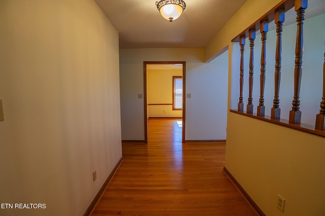 corridor with baseboards and wood finished floors