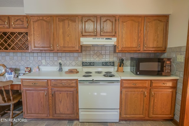 kitchen featuring light countertops, under cabinet range hood, white range with electric cooktop, brown cabinetry, and black microwave