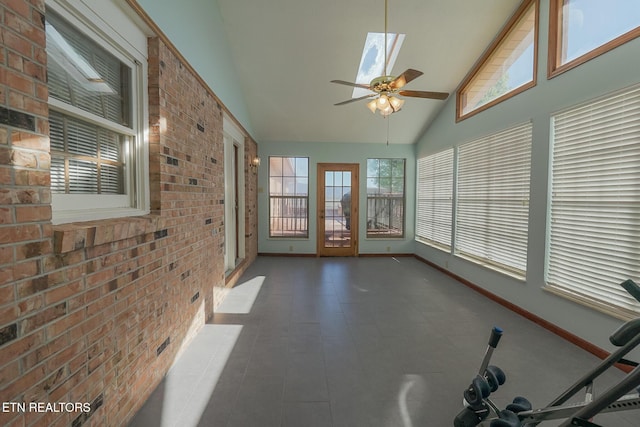 unfurnished sunroom with baseboards, high vaulted ceiling, and brick wall