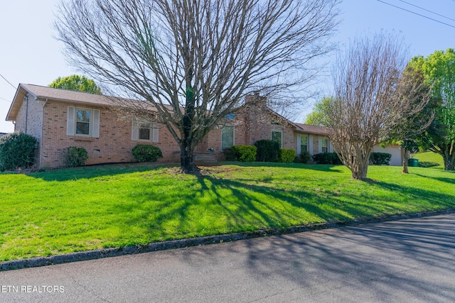 single story home with a front lawn, a chimney, and brick siding