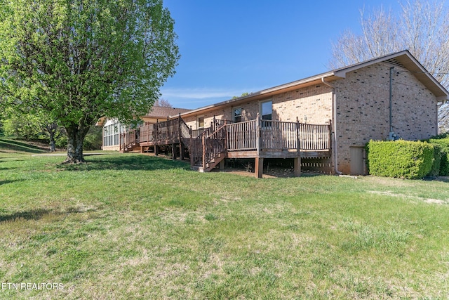 rear view of house featuring a yard, brick siding, stairway, and a deck