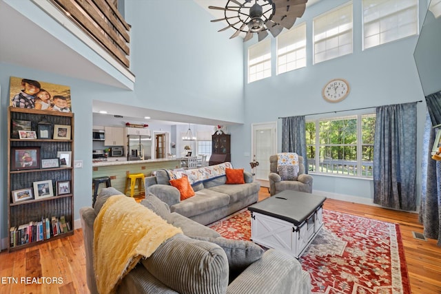 living room with a towering ceiling, light hardwood / wood-style floors, and a healthy amount of sunlight